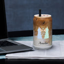 Sheep glass with straw filled with iced coffee and silver straw, placed on a table beside a laptop.